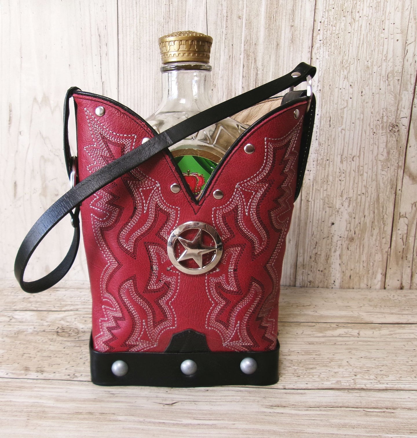 Red leather pouch with cowboy design and bottle inside on a wooden surface